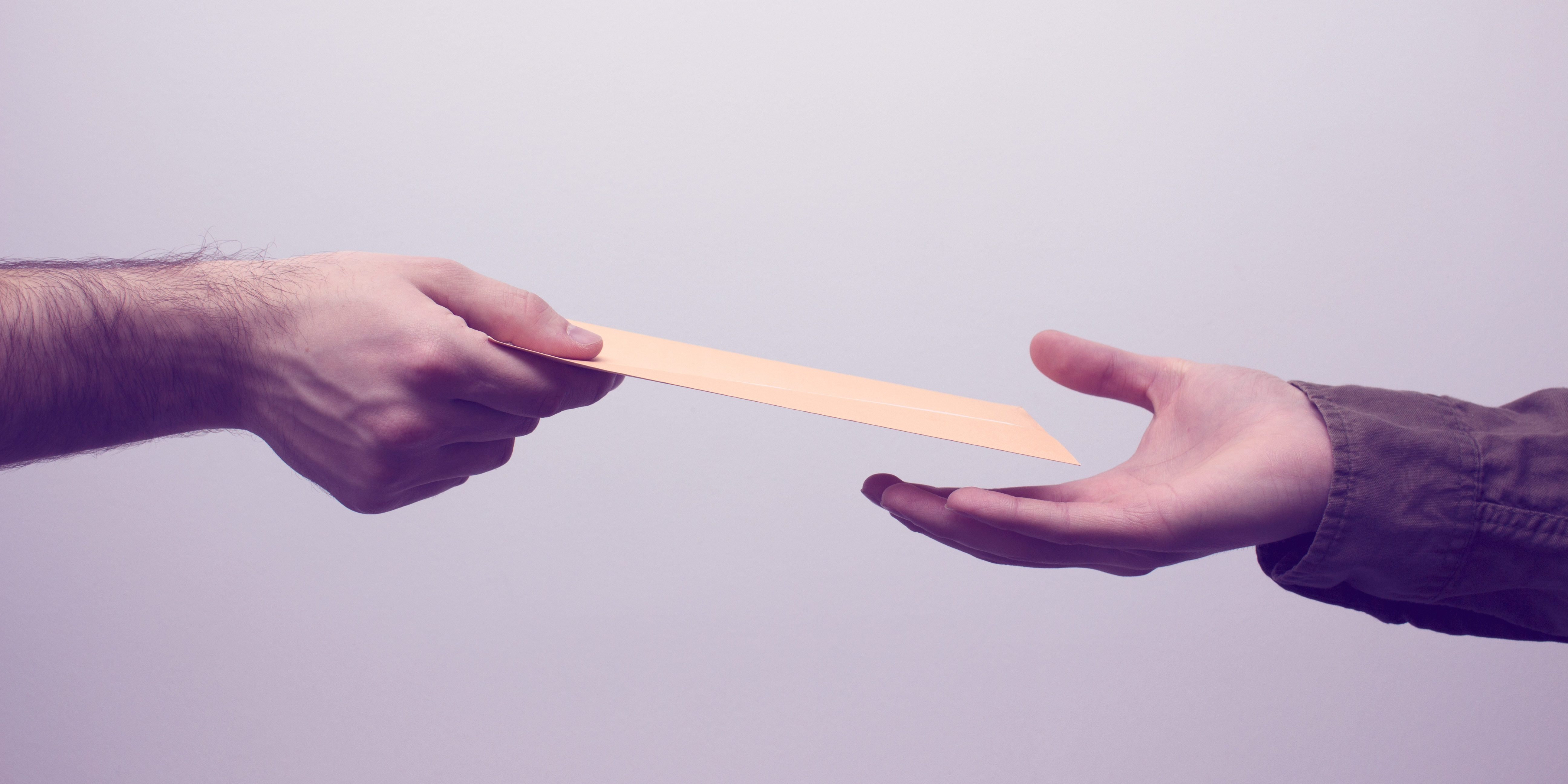 Two men hands receiveng and giving mail in envelope on the white background. Mailtime concept. Close up and toned