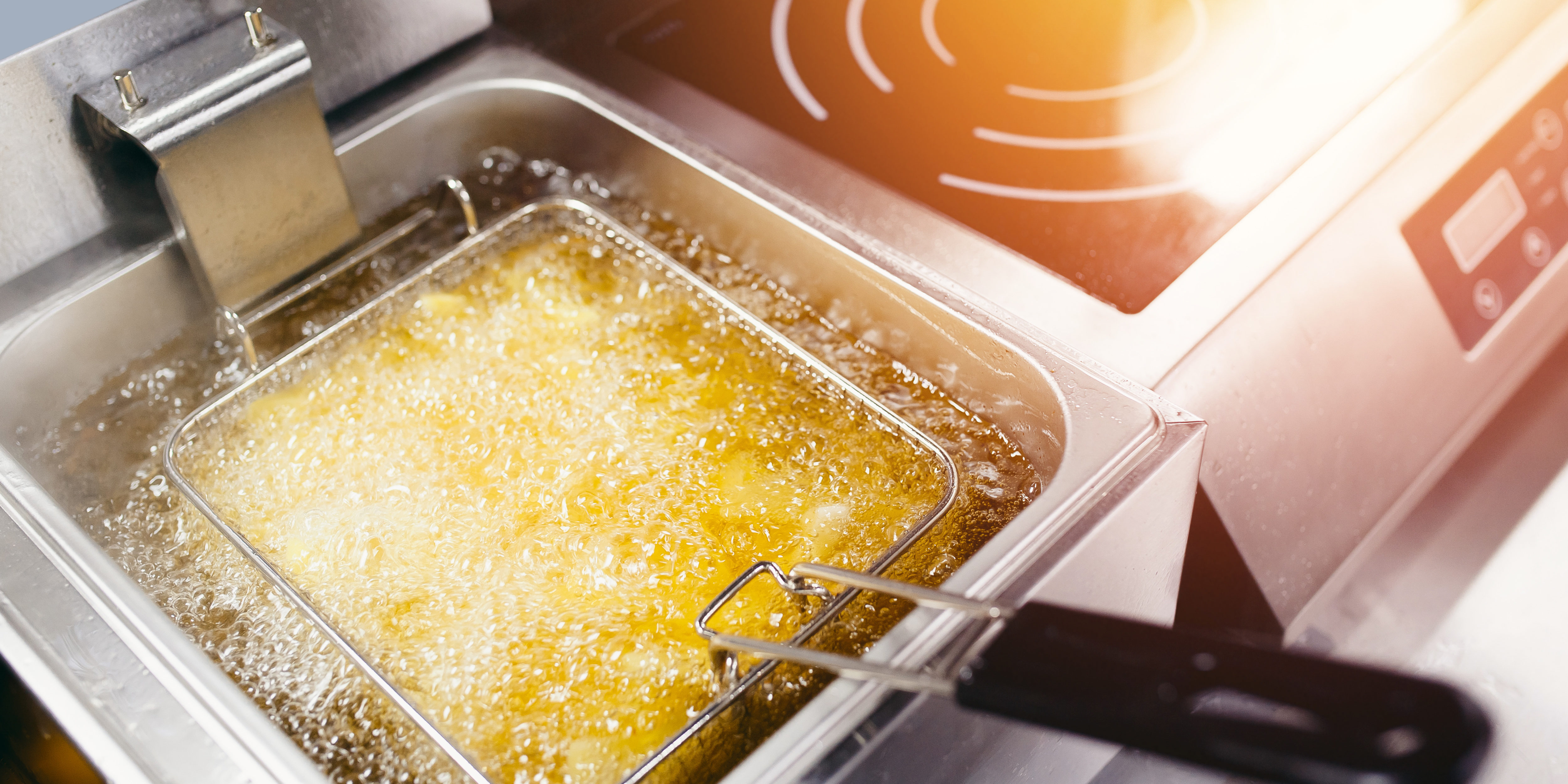 Fryer with French fries, close-up. The oil boils