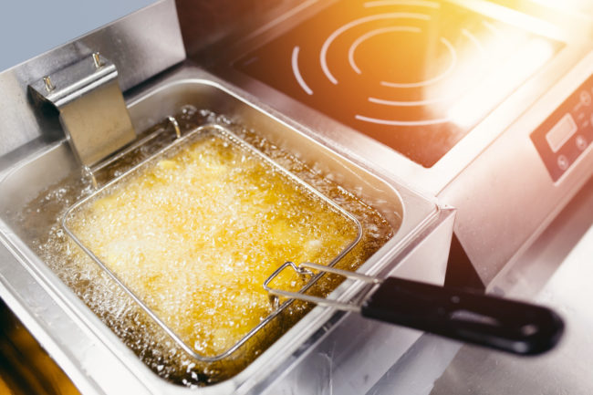 Fryer with French fries, close-up. The oil boils