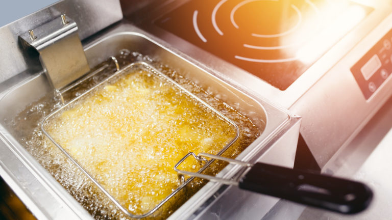 Fryer with French fries, close-up. The oil boils