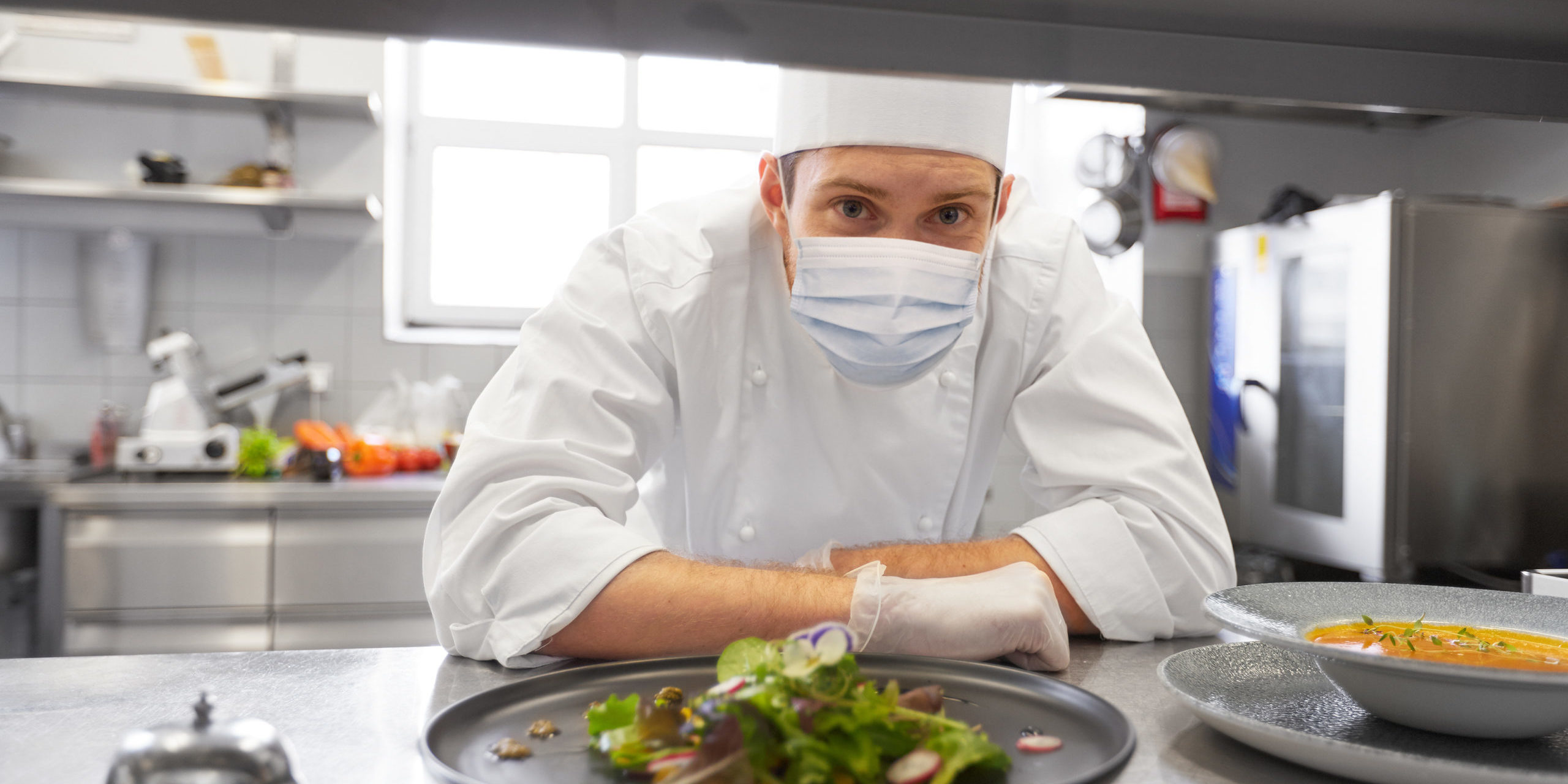male chef in mask with food at restaurant kitchen