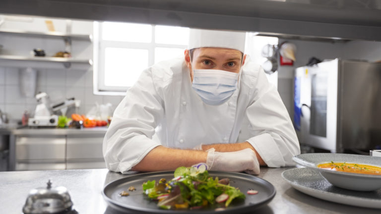 male chef in mask with food at restaurant kitchen